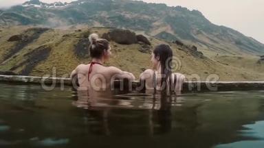 冰岛<strong>温泉</strong>地热<strong>温泉</strong>.. 两位旅行妇女在热池中放松，山上有美丽的风景。